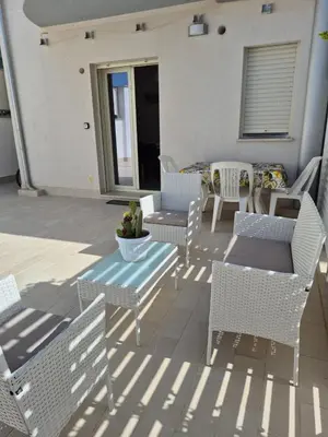 a patio with white chairs and a table and chairs at ammare da mari in Castellammare del Golfo