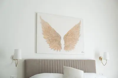 a picture of wings on the wall above a bed at Light Charme, Sun Light Apartment a due passi dalla PIAZZA DUOMO in Terrasini