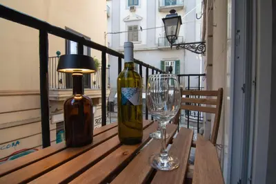a table with two bottles and a wine glass on a balcony at A Calat'i Jurici in Palermo