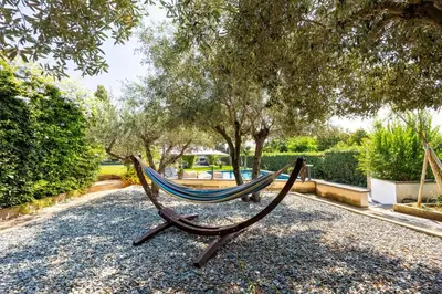 a hammock in a park with trees in the background at Ibis Lodge With Swimming Pool in Palermo