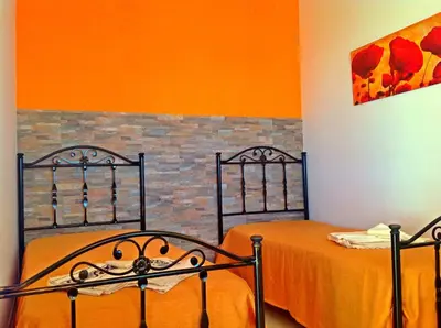a bedroom with two beds and an orange wall at Appartamento Citreum in Balestrate