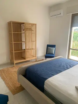 a bedroom with a large bed and a blue chair at Appartamento Citreum in Balestrate