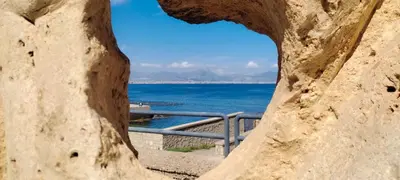 a view of the ocean through a rock window at Aspranthouse in Aspra