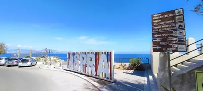 a street sign next to a road with the ocean at Aspranthouse in Aspra