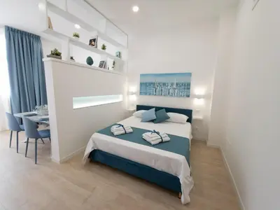 a bedroom with a bed and a dining room at Light Charme, Sea Light Apartment a due passi dalla PIAZZA DUOMO in Terrasini