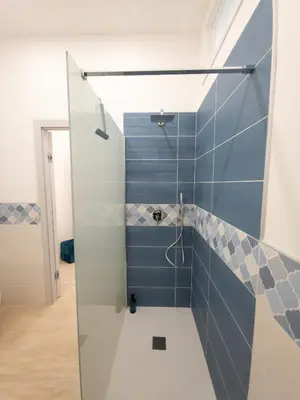 a bathroom with a shower with blue tiles at Light Charme, Sea Light Apartment a due passi dalla PIAZZA DUOMO in Terrasini