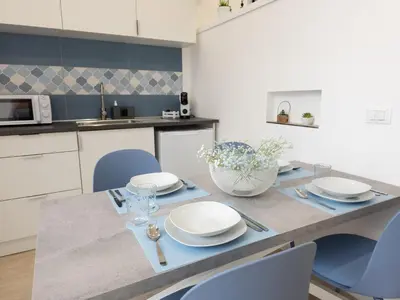 a kitchen with a dining table with blue chairs at Light Charme, Sea Light Apartment a due passi dalla PIAZZA DUOMO in Terrasini