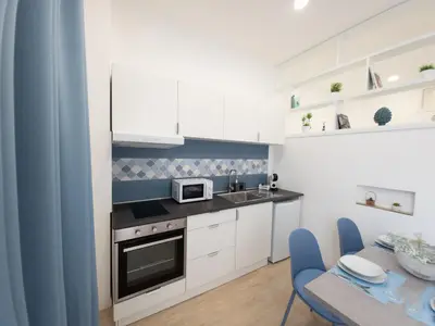 a kitchen with white cabinets and a microwave and a table at Light Charme, Sea Light Apartment a due passi dalla PIAZZA DUOMO in Terrasini