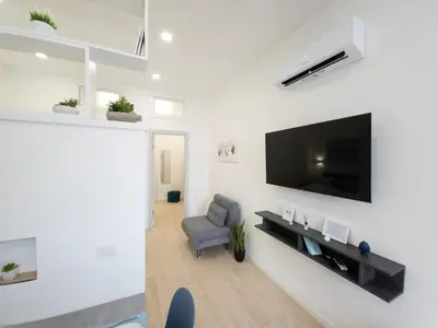 a living room with a tv on a white wall at Light Charme, Sea Light Apartment a due passi dalla PIAZZA DUOMO in Terrasini