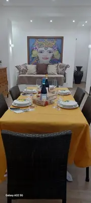 a table with a yellow table cloth and wine glasses at CasaIniso' in Palermo