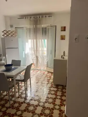 a dining room with a table and chairs and a kitchen at Blue Sea Apartment in Isola delle Femmine