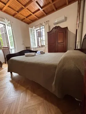 a bedroom with a large bed and wooden floors at House La Cantinetta in Palermo