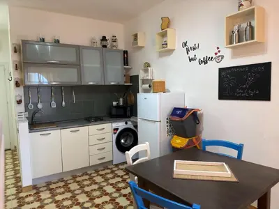 a kitchen with a table and a white refrigerator at Emma's Beach Apartment in Isola delle Femmine