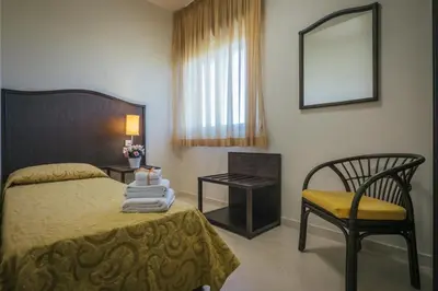 a bedroom with a bed and a chair and a mirror at Hotel Costa Azul in Balestrate