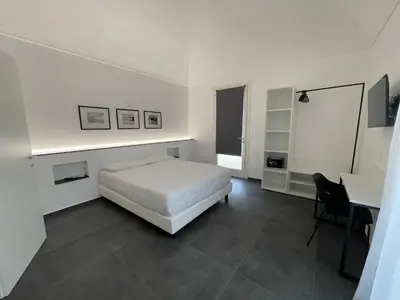 a white bedroom with a bed and a desk at Villa Tosto in Castelluzzo