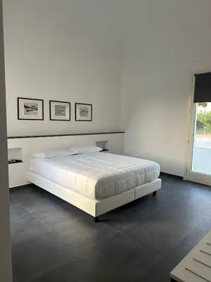 a white bedroom with a bed and a window at Villa Tosto in Castelluzzo