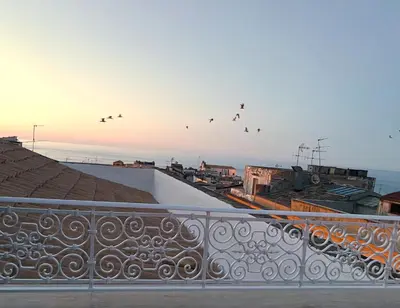 a flock of birds flying in the sky over a balcony at Palazzo 700 in Castellammare del Golfo