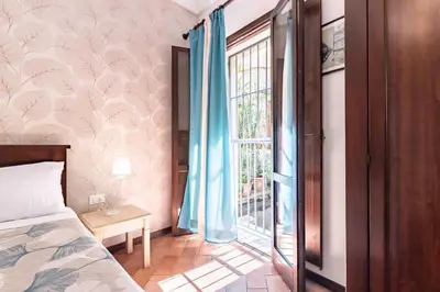 a bedroom with a bed and a window with blue curtains at GuestHost - La Maison Real Palermo in Palermo