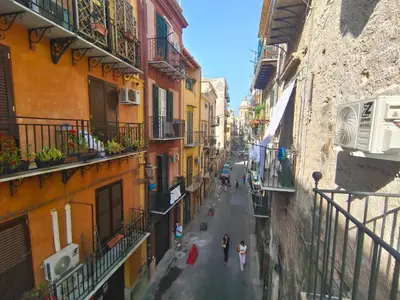 a group of people walking down a street between buildings at Atypical Rooms in Palermo