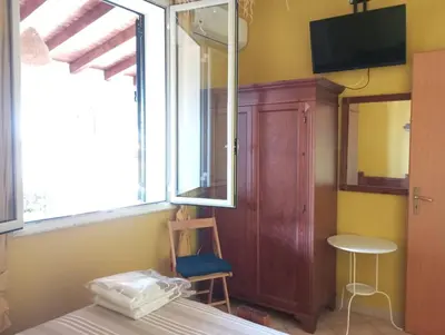 a bedroom with a bed and a chair and a tv at Mami house in Sambuca di Sicilia