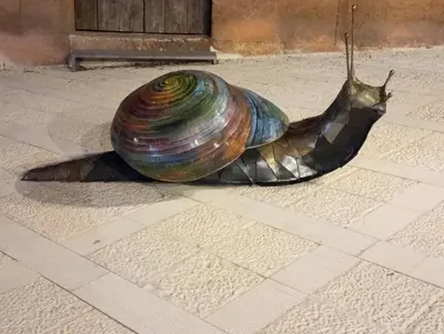 a snail statue sitting on the ground on a sidewalk at Mami house in Sambuca di Sicilia