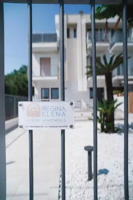 a sign on a fence in front of a building at Regina Elena Luxury Apartments in Mondello
