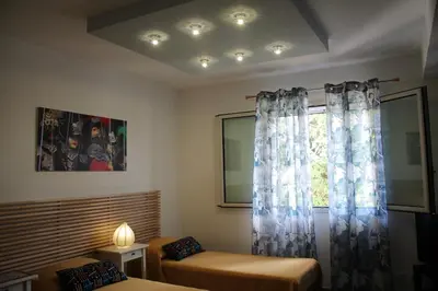a room with two beds and a window with curtains at Baia del Sol Balestrate in Balestrate