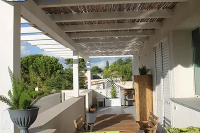a patio with a pergola and chairs on a house at Baia del Sol Balestrate in Balestrate