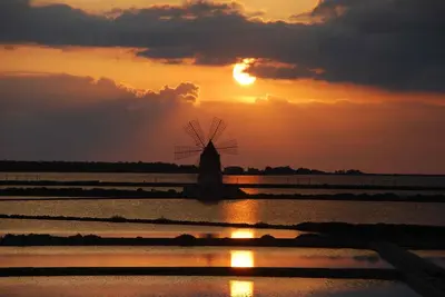 a windmill in a field with the sunset in the background at Baia del Sol Balestrate in Balestrate