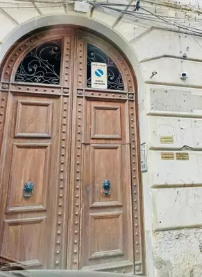 a wooden door on a building with a sign on it at La dimora di Aurora in Palermo