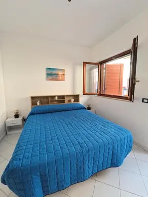 a bedroom with a large bed with a blue bedspread at Ciatu di Suli in San Vito lo Capo