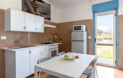 a kitchen with white cabinets and a table with chairs at Stunning Apartment In Balestrate in Balestrate