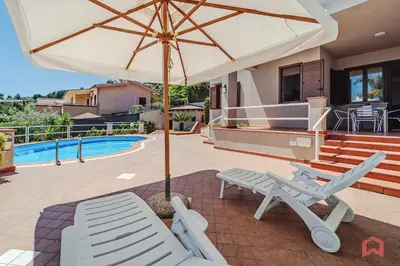 a patio with an umbrella and chairs and a pool at Delizioso Appartamento in villa & Piscina Privata in Trabia