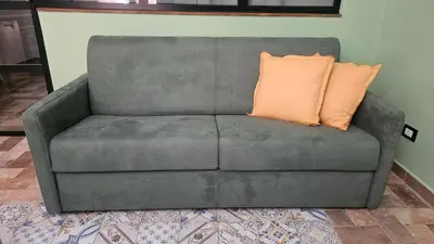 a gray couch with an orange pillow on it at Barbarò Apartments in Palermo