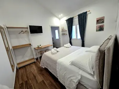 a bedroom with a white bed and a television at Angelina Rooms in Palermo