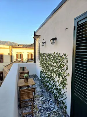 a balcony with a table and a wall with plants at Angelina Rooms in Palermo