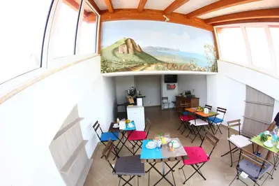 a room with tables and chairs and a painting on the wall at B&B Menta & Peperoncino in Partinico