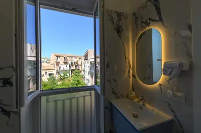 a bathroom with a mirror and a sink and a window at Oros rooms in Palermo