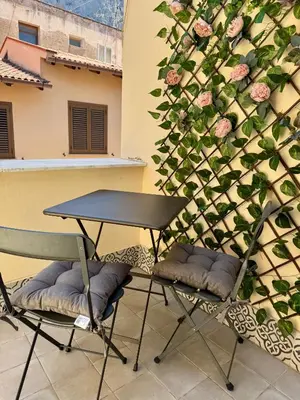 a table and two chairs next to a wall with roses at La Casetta dell'Architetto in Cinisi