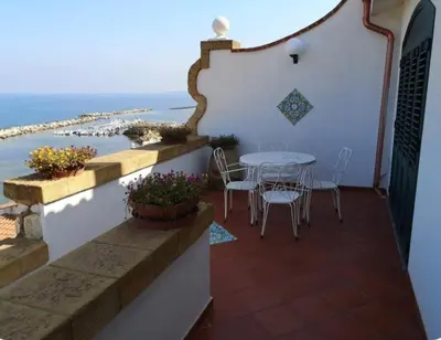 a balcony with a table and chairs and the ocean at Villa Adele in Trappeto