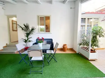 a patio with a table and chairs on a green rug at Il Vialetto in Mondello