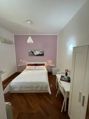 a bedroom with a white bed and a purple wall at Dimora 51 in Palermo
