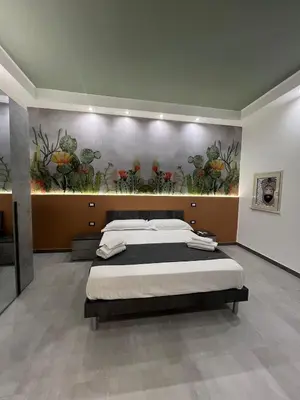 a bedroom with a large bed with a painting on the wall at kumpa' sicilian apartments in Palermo
