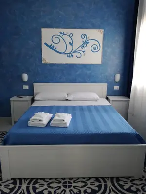 a blue bedroom with a bed with towels on it at Benvenuti al Sud B&B in Macari