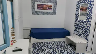 a small room with a bed and a blue and white floor at Benvenuti al Sud B&B in Macari