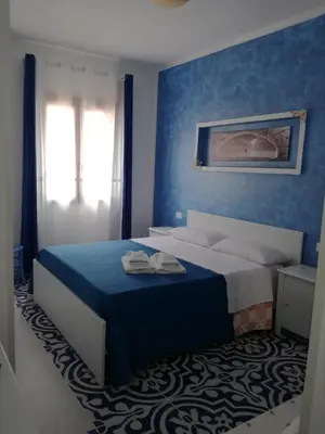 a blue bedroom with a bed and a window at Benvenuti al Sud B&B in Macari