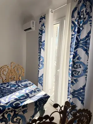 a bedroom with blue and white curtains and a window at Opera Dolce in Carini
