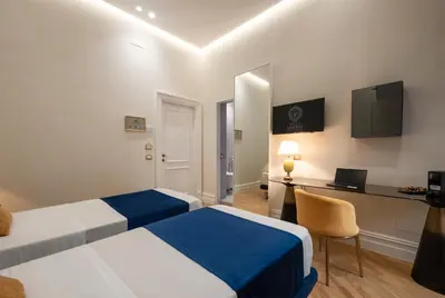 a hotel room with two beds and a desk at Villa Libertà in Palermo