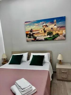 a bedroom with two beds and a painting on the wall at Santerasmo Rooms standard in Palermo