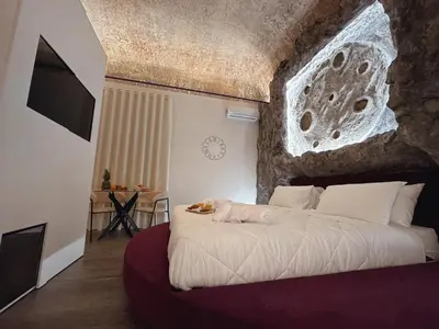 a bedroom with a white bed with a stone wall at Corona Suite & Rooms in Palermo